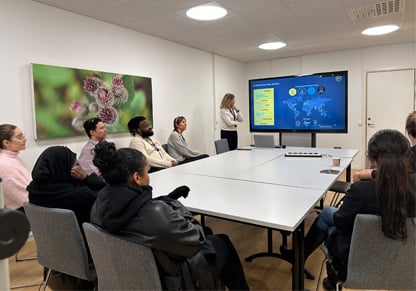 An Intertek colleague presents in front of a group of young people around a large table. 